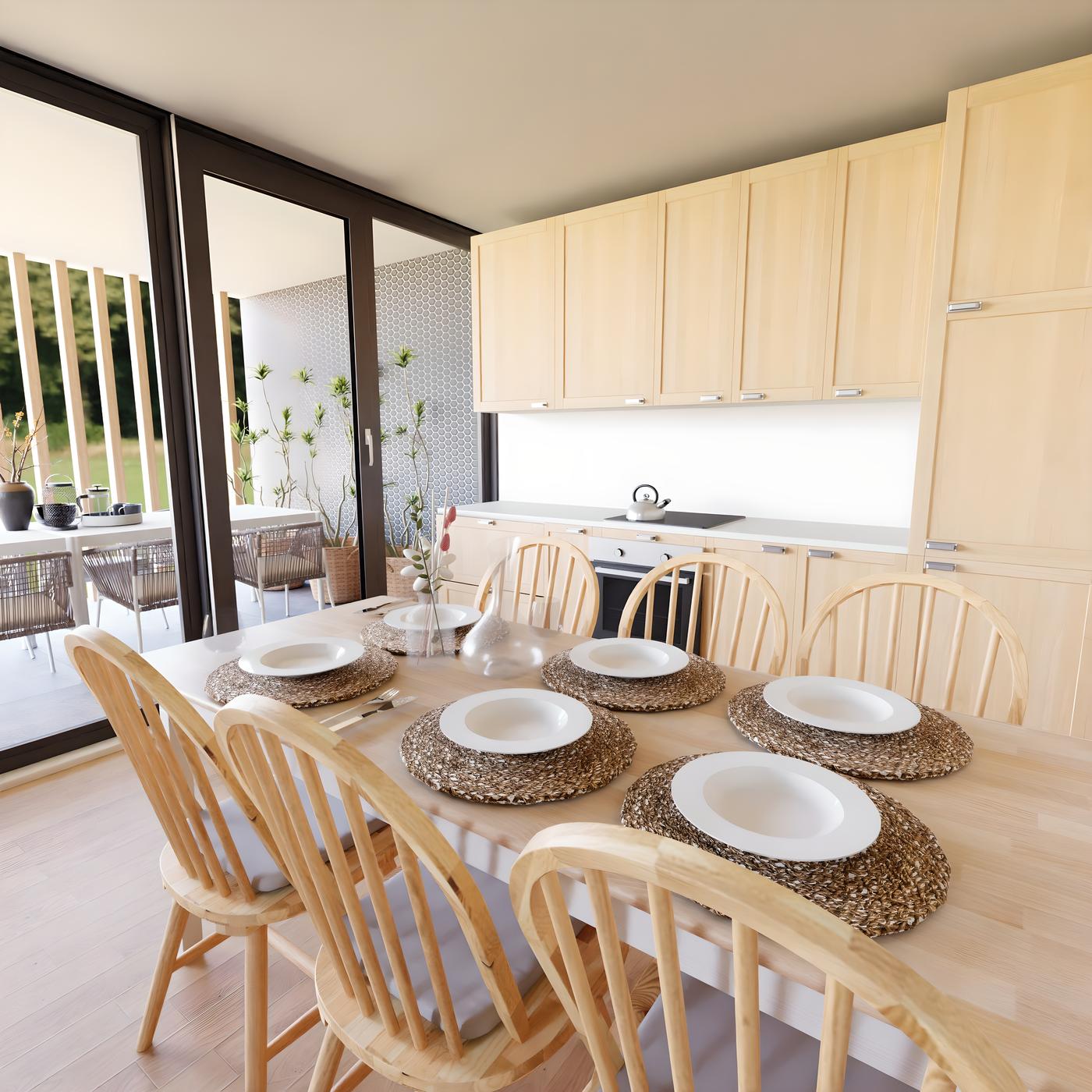 Blagovaonica s drvenim stolom i stolicama, šest tanjura na podmetačima, kuhinja u pozadini i terasa s biljkama.
