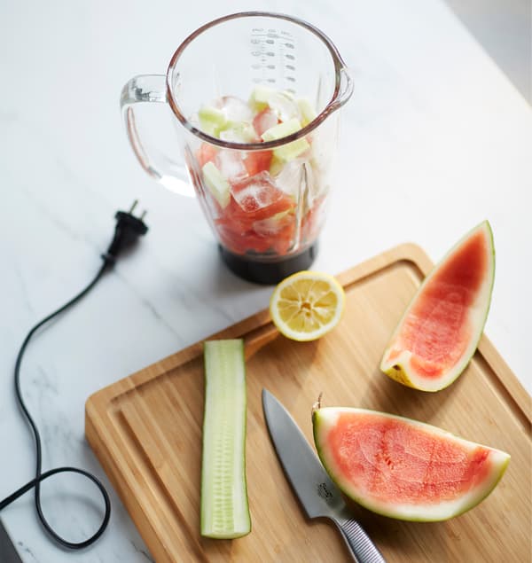 Blender rempli des ingrédients pour le smoothie, posé sur un plan de travail.