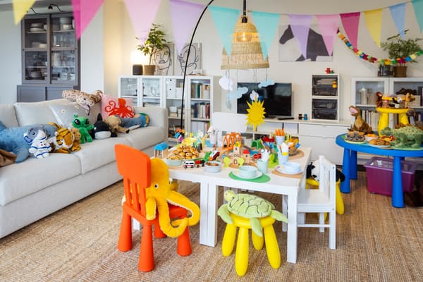 Blick auf den Geburtstagstisch. Viele Stofftiere sind eingeladen. Bunte niedriege Kinderstühle, auf dem Couchtisch wird das Essen in angenehmer Höhe serviert.