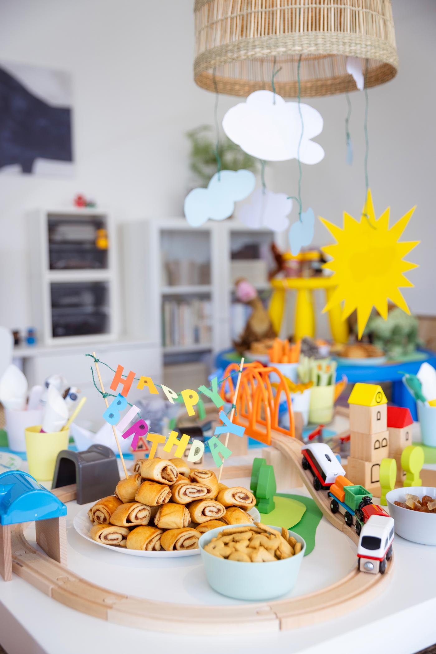 Blick auf den geschmückten Tisch. Die LILLABO Holzeisenbahn fährt um Telelr und Schüsseln herum. 