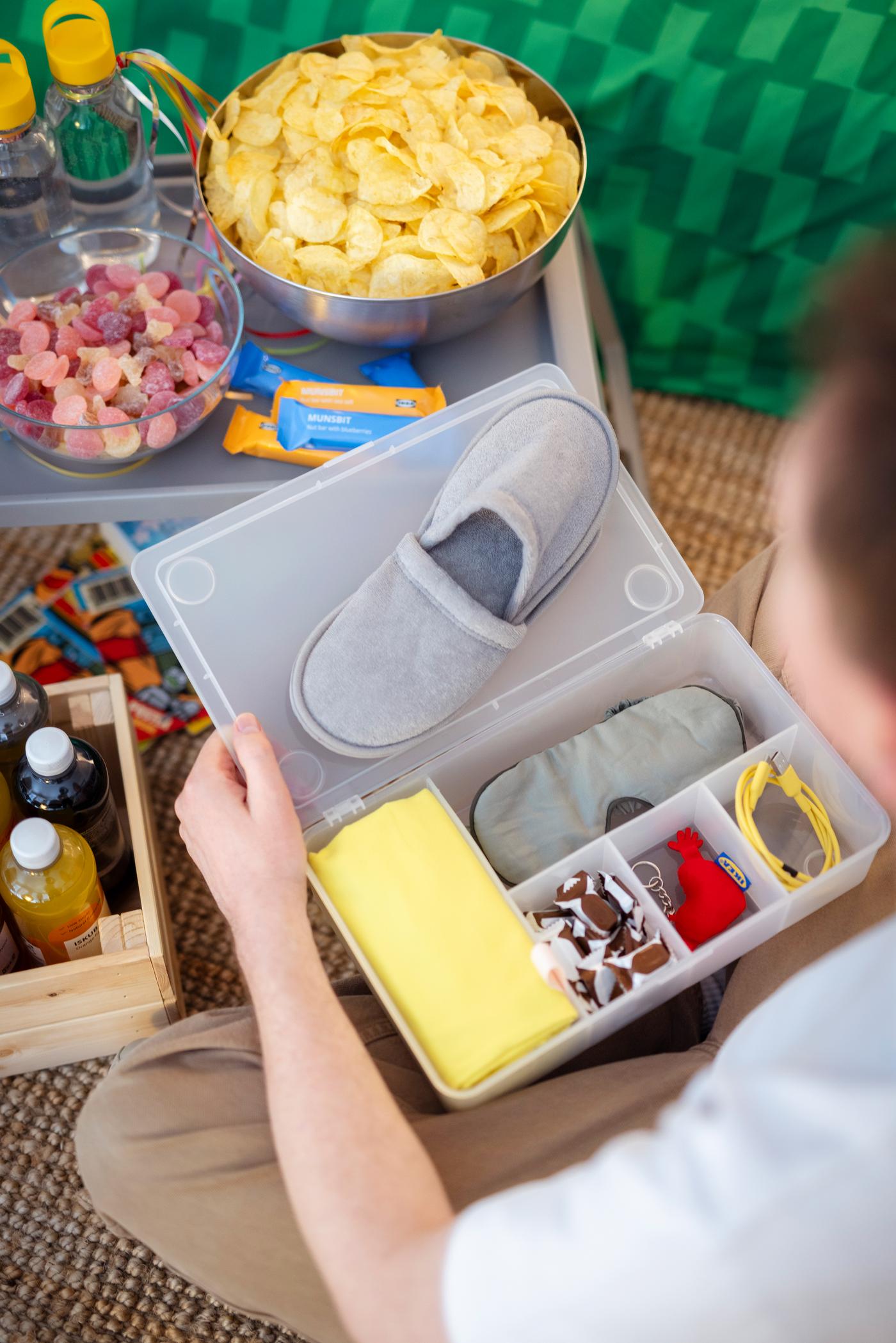 Blick in die offene Willkommensbox mit Schlafmaske, Handtuch und Ladekabel. 