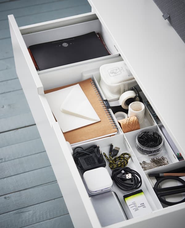 Blick von oben auf eine Schublade mit Fächern, in denen Schere, Klebestreifen, Kabel und Co. organisiert sind.