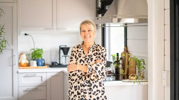 Bloggaaja Maarit Veromaa hymyilee modernin mökkinsä vaaleanharmaassa, perinteisessä LERHYTTAN-keittiössä.