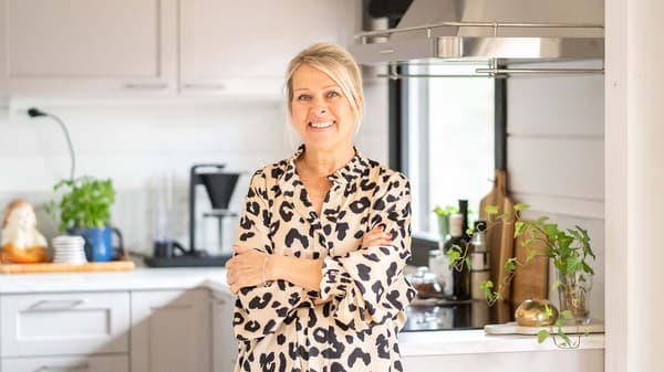 Bloggaaja Maarit Veromaa hymyilee modernin mökkinsä vaaleanharmaassa, perinteisessä LERHYTTAN-keittiössä.