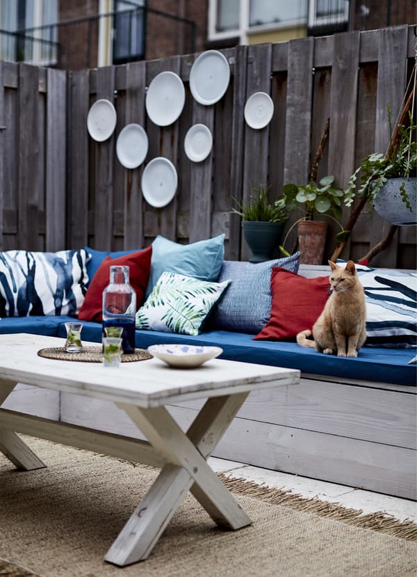 Blue and red cushions along a wooden bench.