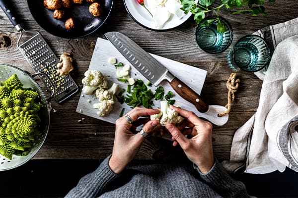 Blumenkohl wird für vegetarisches Blumenkohl-Curry klein geschnitten.