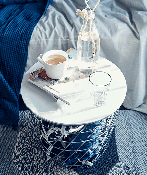 Boissons et magazines sur une table d’appoint avec du rangement en-dessous.