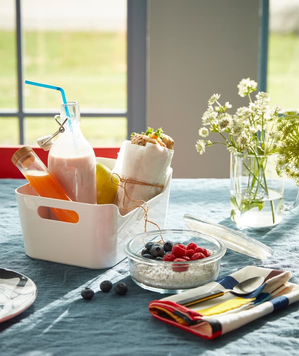 Boîte blanche VARIERA contenant un petit déjeuner à emporter composé d’un sandwich, d’une bouteille en verre remplie de yoghourt et de jus.