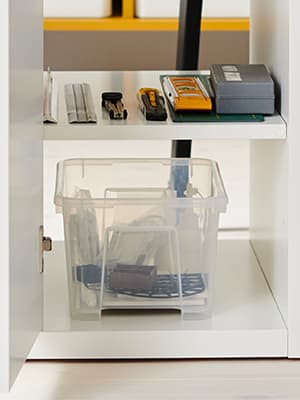 Boite de rangement SAMLA transparente rangée dans un bureau.