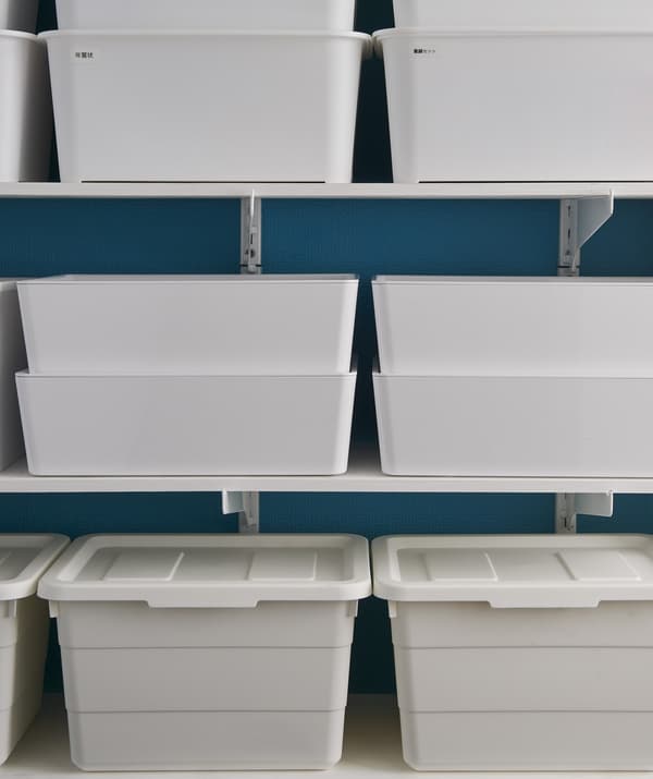 Boîtes de rangement blanches empilées sur des tablettes.