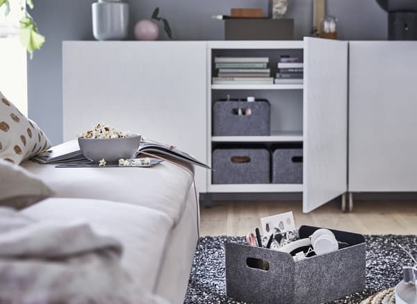 Boîtes de rangement grises dans un meuble de rangement bas blanc.