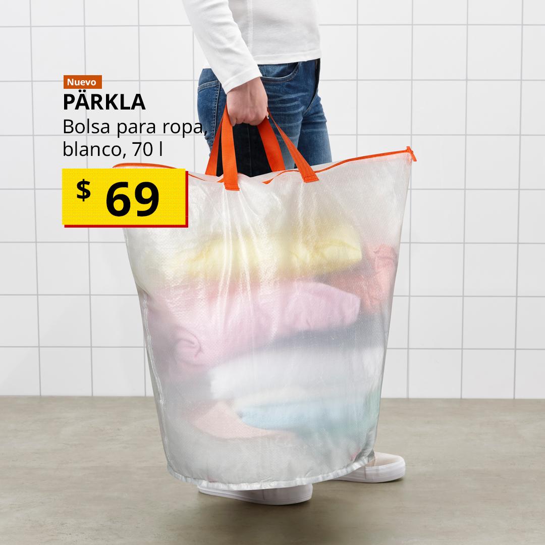 Bolsa para ropa PÄRKLA blanca con asas naranjas, llena de ropa y sostenida por una persona.