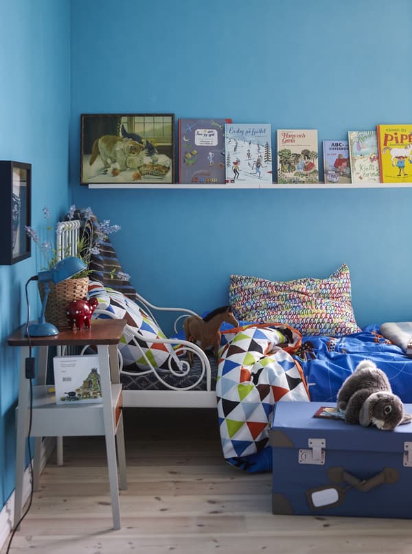 Books on display on a shelf in a child’s bedroom painted blue.