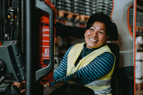 Booni, medewerker bij IKEA zit op een truck. Ze heeft een blauw gestreept T-shirt aan met een geel hesje eroverheen.