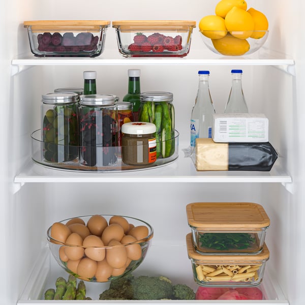 Bottles and jars are placed on a rotating KLIPPKAKTUS turntable for easy access inside a fridge, alongside other food items on the shelves.