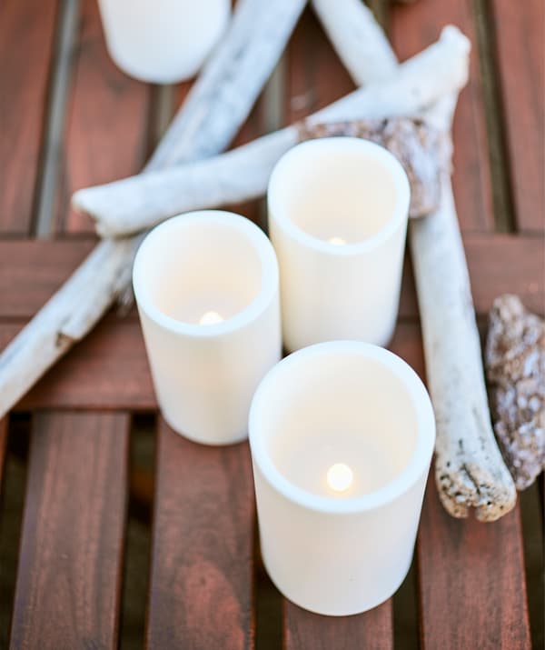 Bougies blocs à LED sur une table en bois avec du bois flotté.