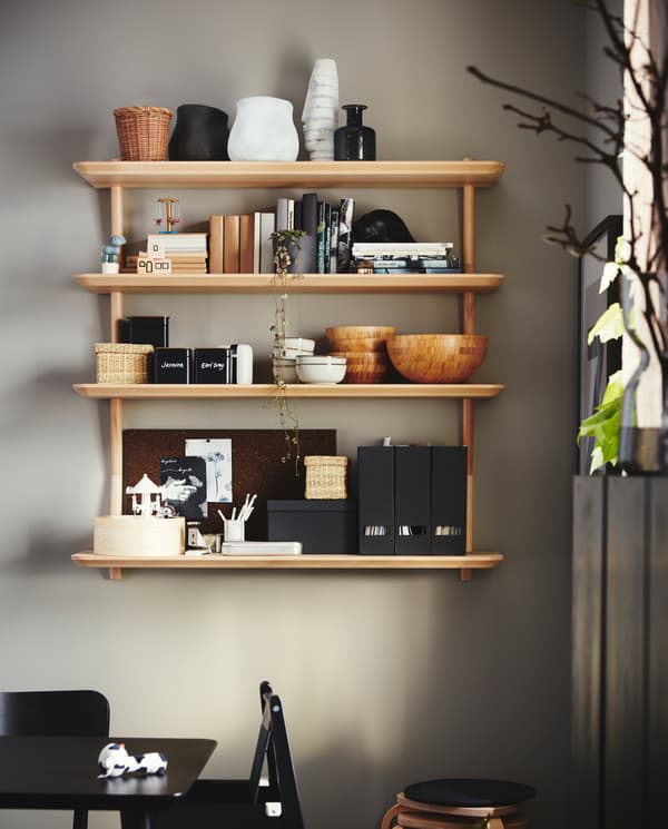 Bowls, magazine files, crockery and books are stored on four wall shelves in ash veneer that are wall-mounted by a table.