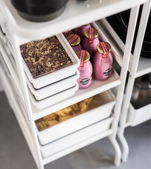 Boxed up granola and drinks placed on a tiny pantry's white stainless steel shelves from the IKEA SUNNERSTA series.