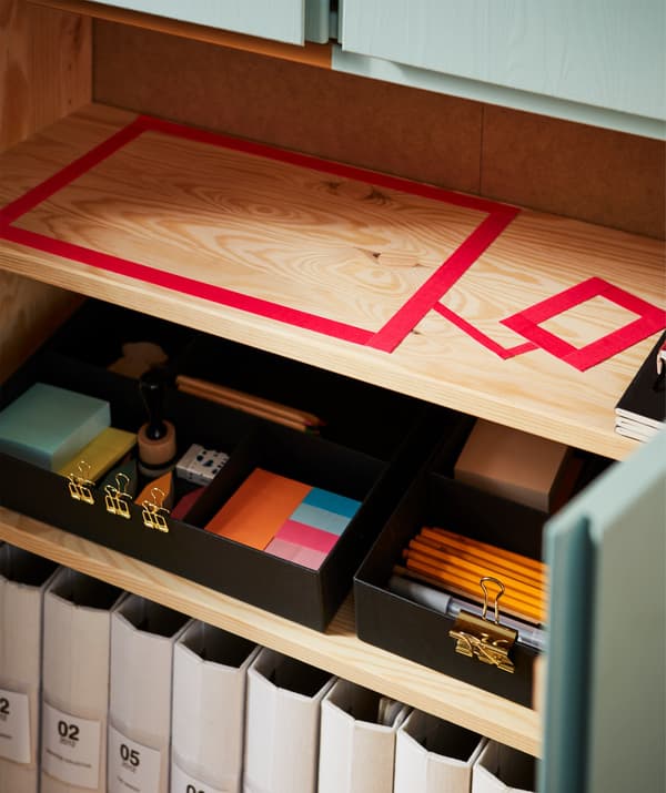 Boxes and files on shelves and a taped outline zone for a computer.