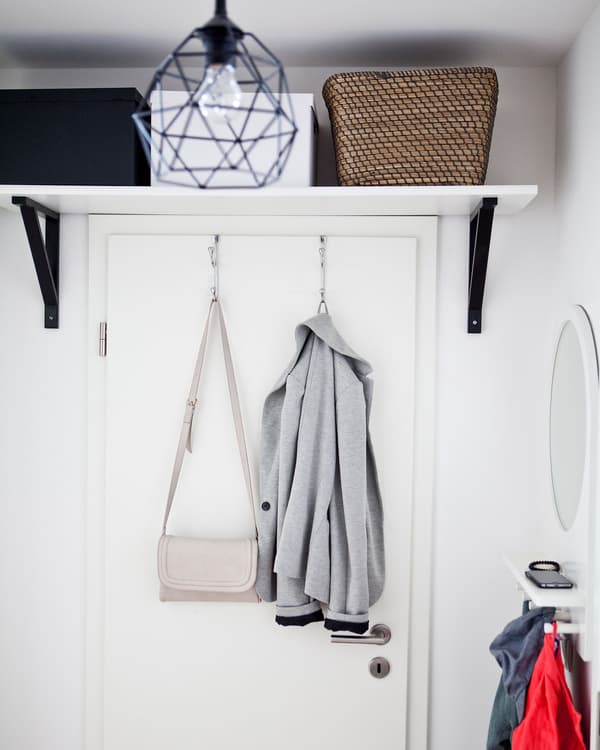 Boxes stored on a shelf above a door in a white hall.