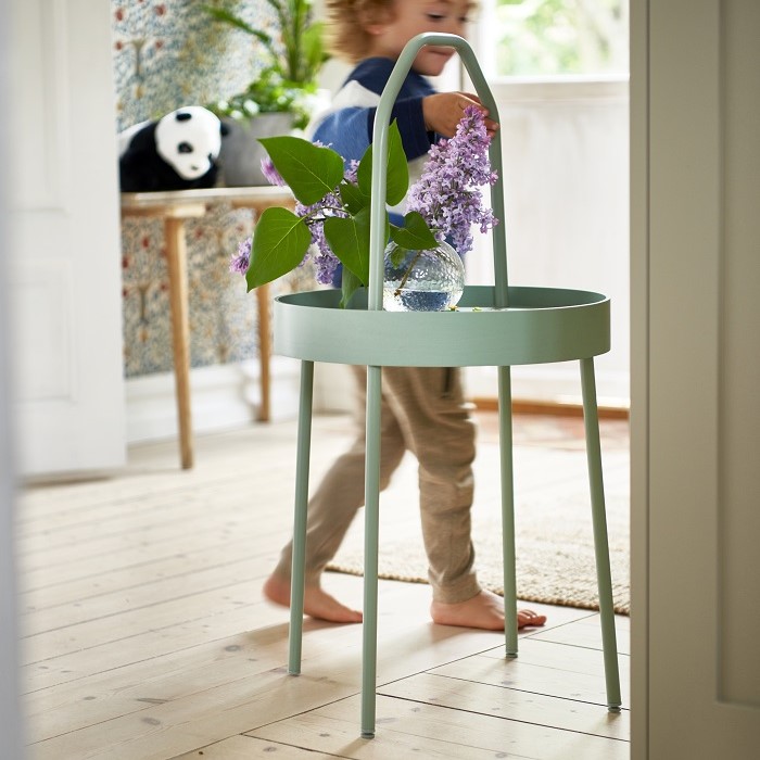 Boy is walking around a green table with flowers on it