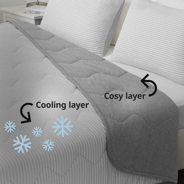 BRANDLILJA cooling duvet on bed. Text with arrow pointing to the striped side of duvet reads: Cooling layer. Five light blue snowflakes surround the striped side of duvet. On the right, text with arrow pointing to the jersey side of duvet reads: Cosy layer