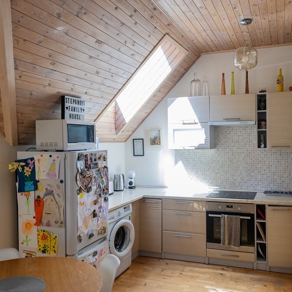 Bright attic kitchen with wooden cabinets, skylight window, and cozy dining corner