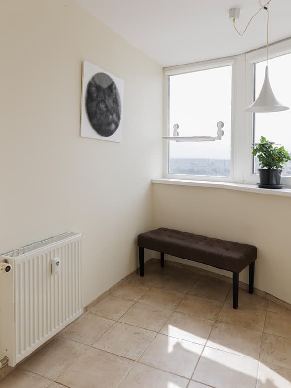 Bright corner with a bench under the window and beige tiled floor.