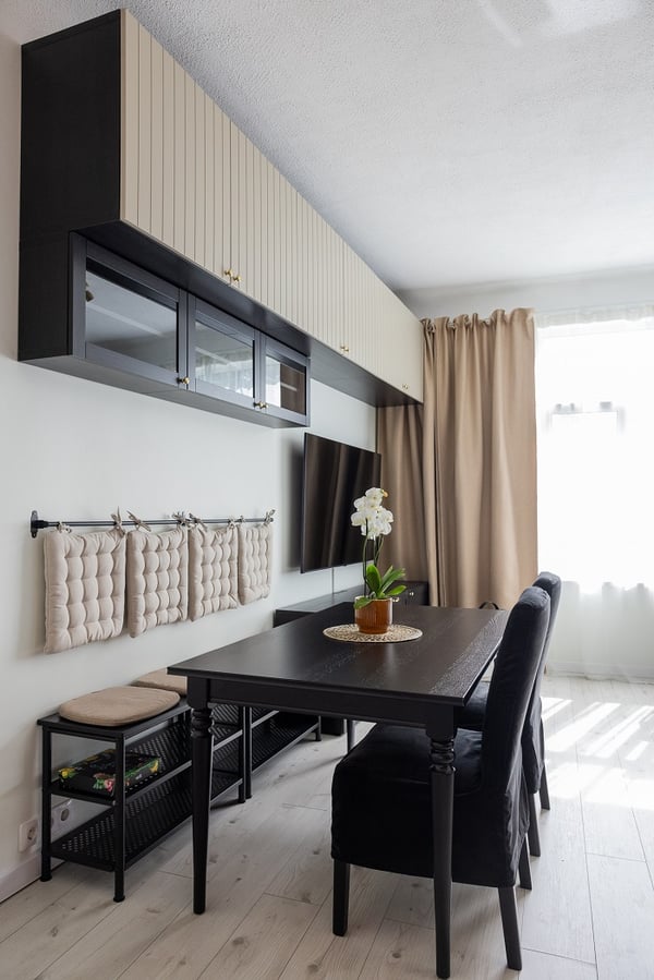 Bright dining space with black dining table, wall-mounted TV, and neutral curtains