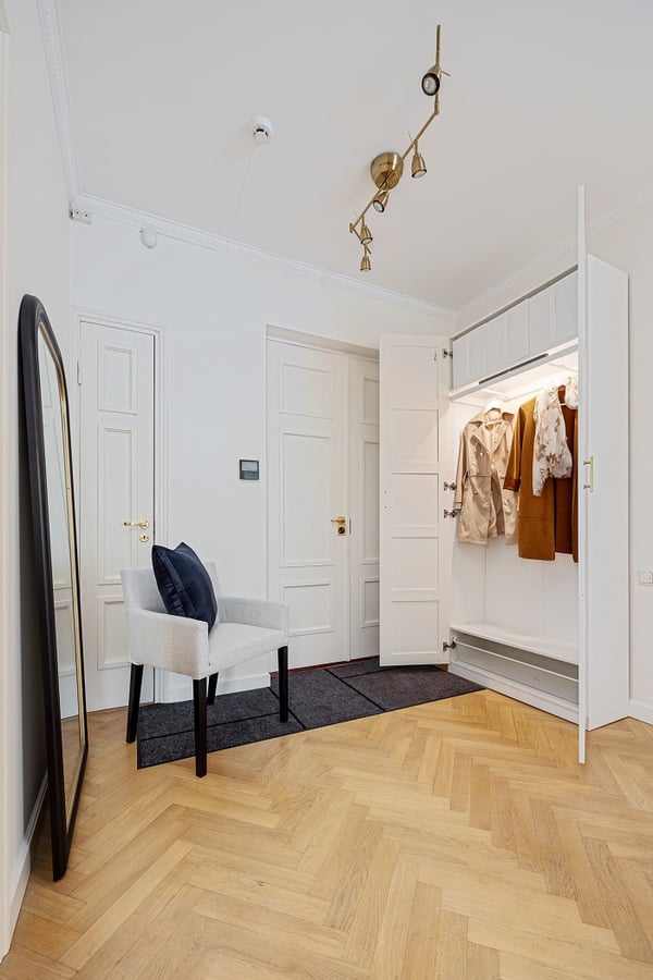 Bright hallway with open wardrobe showing coats and modern ceiling light