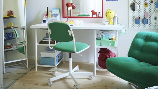 Bright home workspace with white desk, green chair, mirror, wall organizer, and colorful decor and supplies.