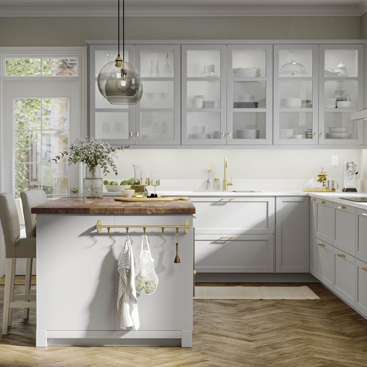 Bright kitchen with light gray cabinets, wood accents and a central island with stools.