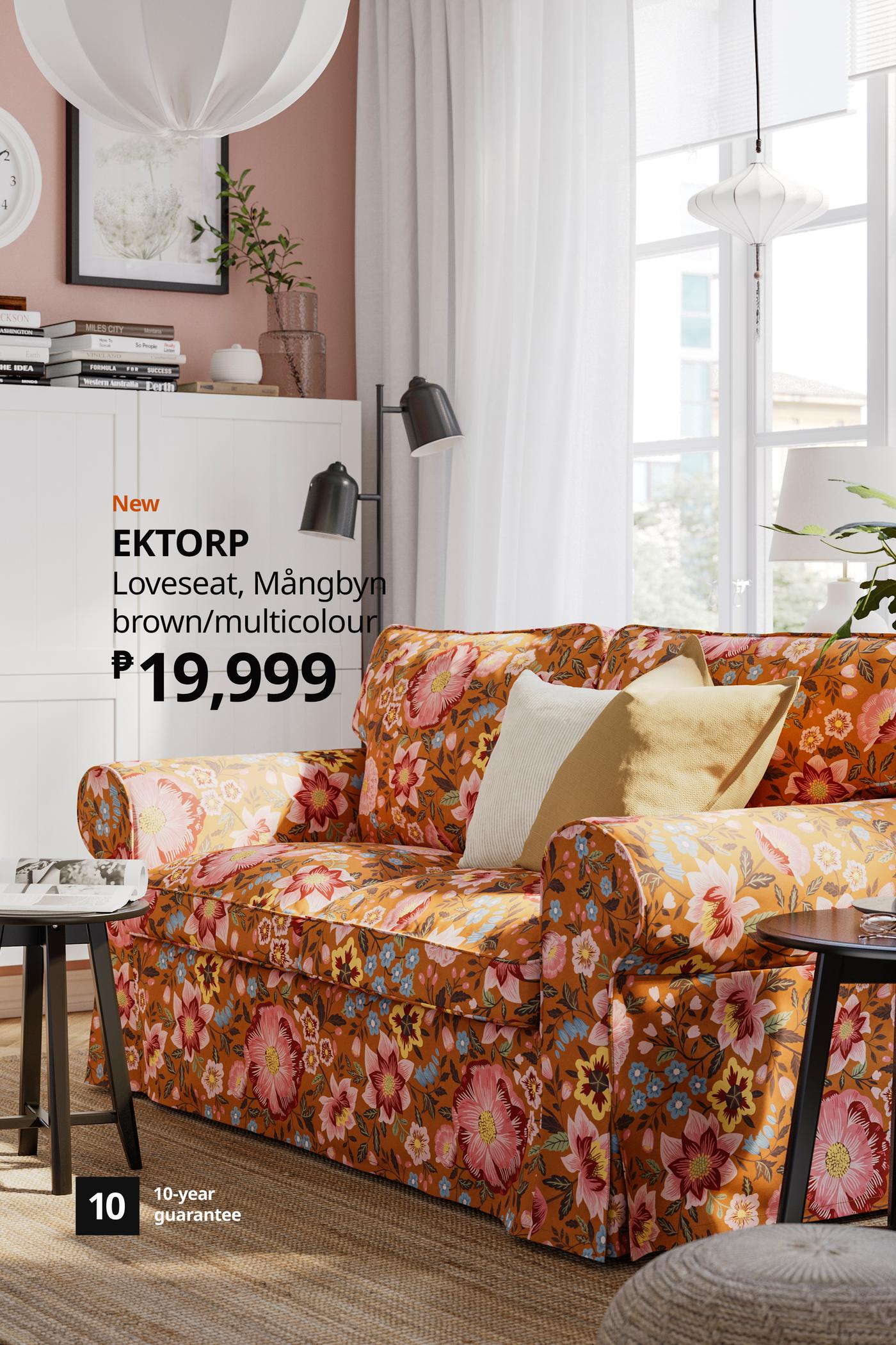 Bright living room with an orange floral EKTORP loveseat, cream cushions, white cabinets and sheer curtains; price 19,999, cozy atmosphere.