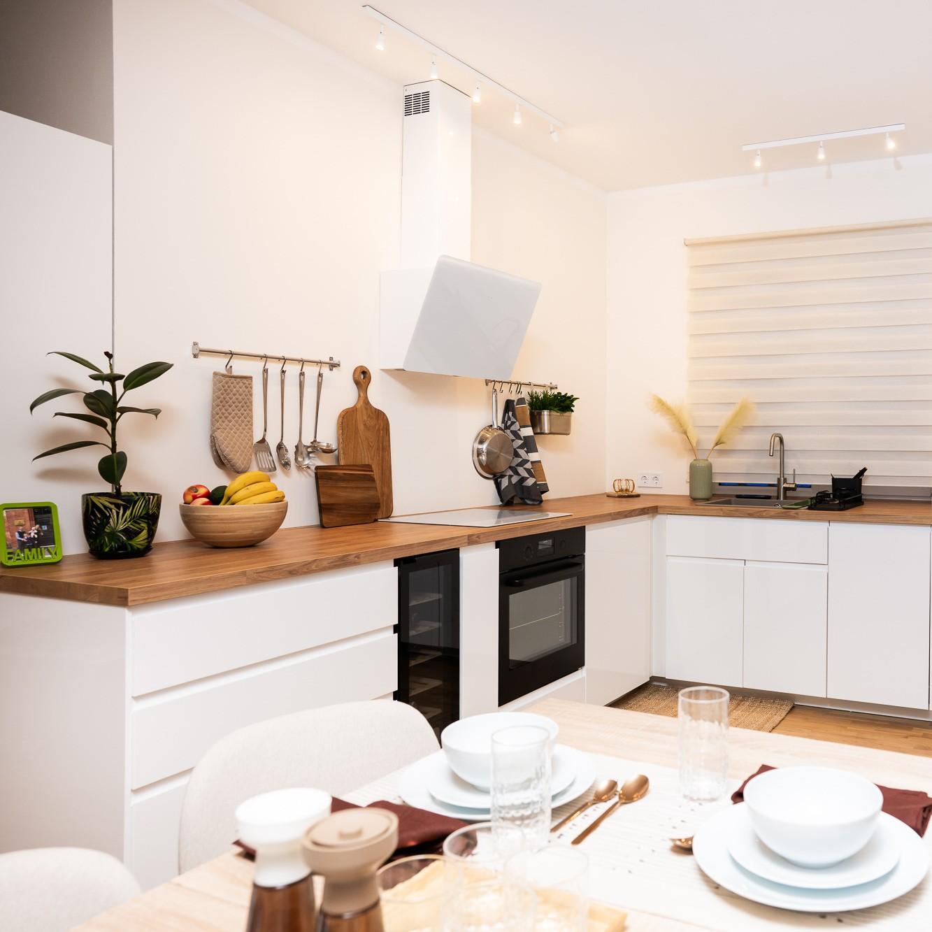 Bright, modern kitchen with white cabinet fronts and wooden worktops; the table is set for a meal, and the space feels tidy and cohesive.