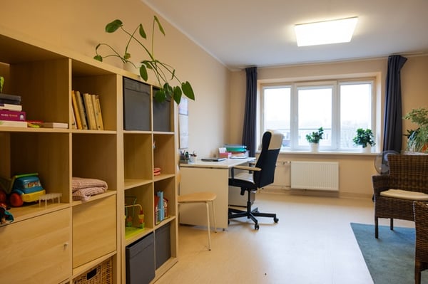Bright room before interior makeover with yellow walls, open shelves, and a desk.