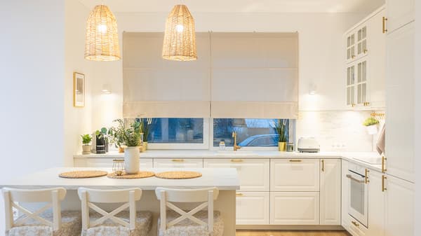 Bright Scandinavian style kitchen with kitchen island, pendant lamps, and stools.