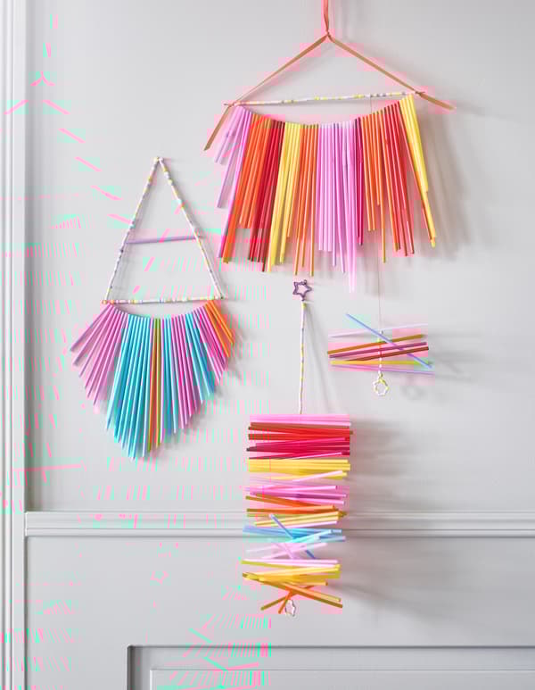 Brightly coloured decorative wall hangings made from drinking straws.