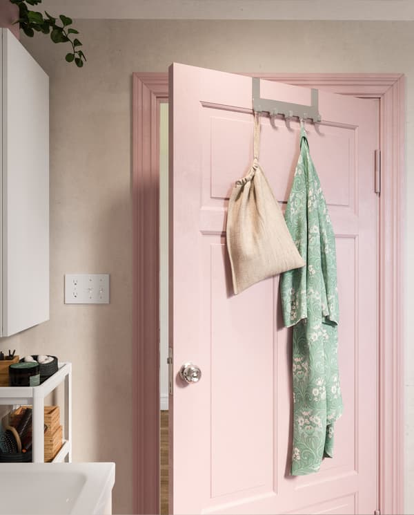BROGRUND hanger for door in stainless steel hangs on a pink bathroom door. A turquoise bathrobe hangs on one of the hooks.