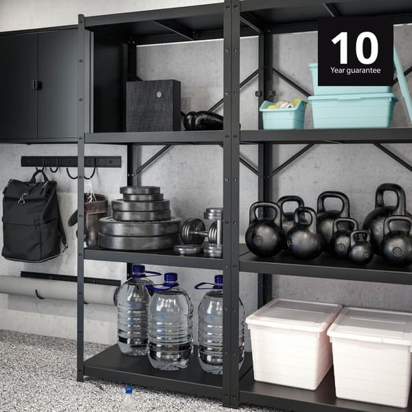 BROR heavy duty shelving rack with 10-year guarantee holding gym equipment, heavy weights and secondary storage boxes next to hooks on wall and a shelving cabinet with doors. 