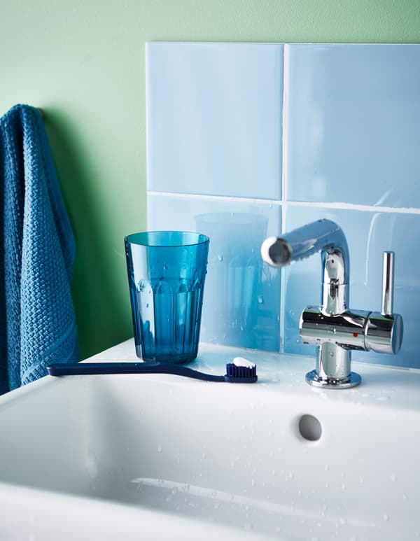 Brosse à dents et petit verre en plastique déposés sur le lavabo