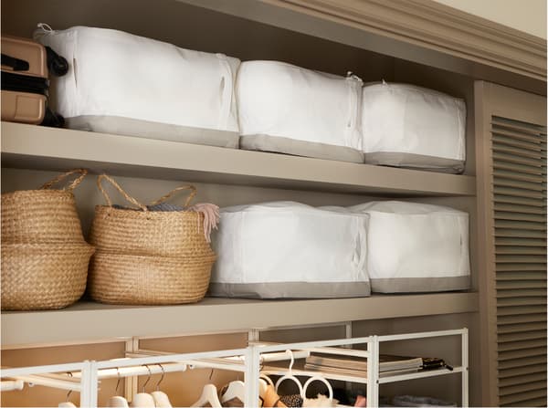 Built-in hallway wardrobe with white IKEA LACKISAR storage cases stored on the upper shelves together with seagrass baskets.