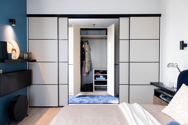 Built-in wardrobe with open doors revealing organized storage in contemporary bedroom