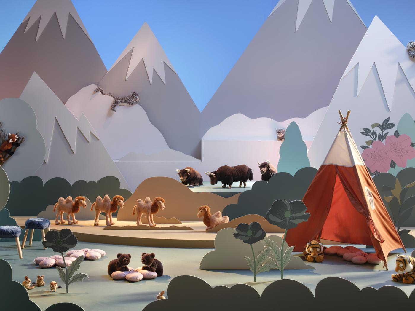 Bunte Kinderzimmerdekoration mit Kuscheltieren der IKEA ALPTALL Kollektion, Pflanzenmotiven und pastellfarbenen geometrischen Formen, die Berge darstellen.