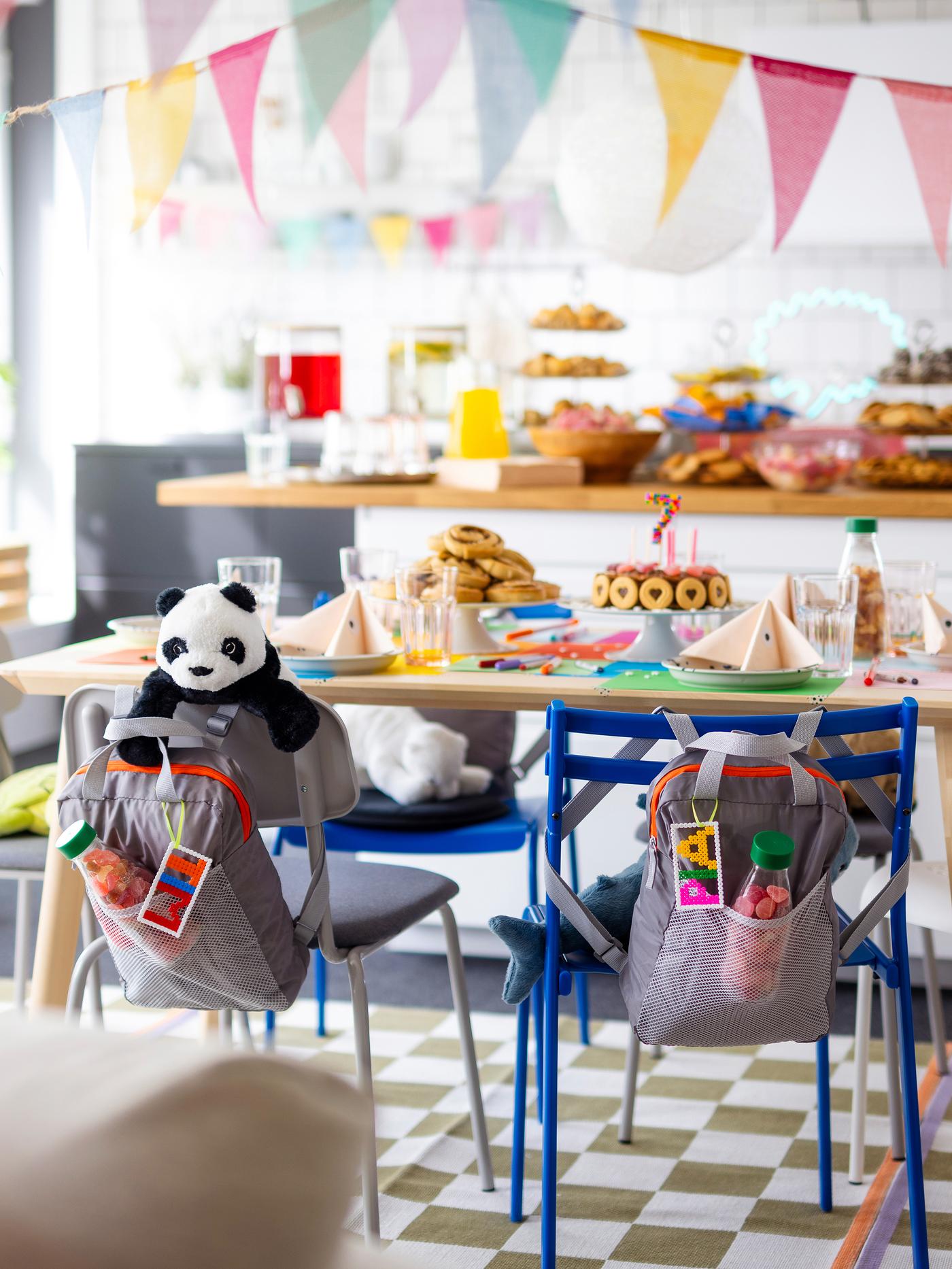 Bunter Geburtstagstisch. An den Stühlen hängen als Gastgeschenk Rucksäcke.