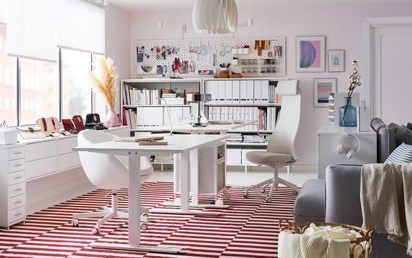 Bureau à domicile blanc, décoré d'un tapis tissé à plat STOCKHOLM en blanc et rouge, avec rangement blanc sur roulettes BEKANT et tiroirs blancs GALANT.