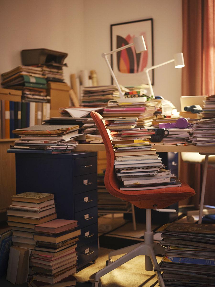 Bureau mal rangé avec une accumulation de documents et de livres sur les meubles de bureau et sur la chaise de bureau