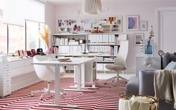 Bureau tout blanc agrémenté d’un tapis tissé plat STOCKHOLM rouge et blanc, d’un caisson sur roulettes BEKANT et d’un meuble à tiroirs GALANT.