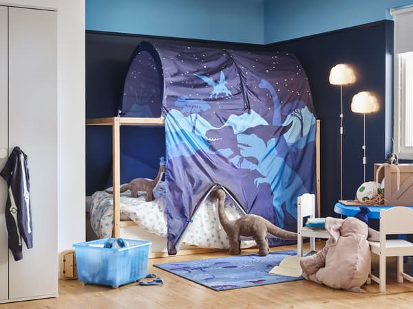 ブルーの布で囲ったプレイエリア付き二段ベッド。恐竜モチーフの装飾で冒険感のある子ども部屋。