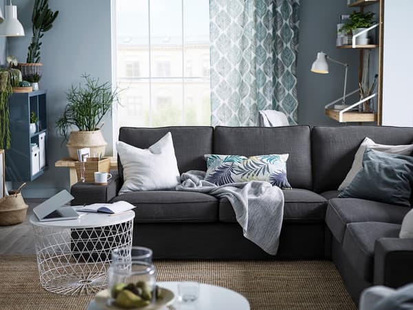 ブルーの壁にグレーソファを置いた落ち着いたリビング。白いクッションとラグで爽やかな雰囲気。