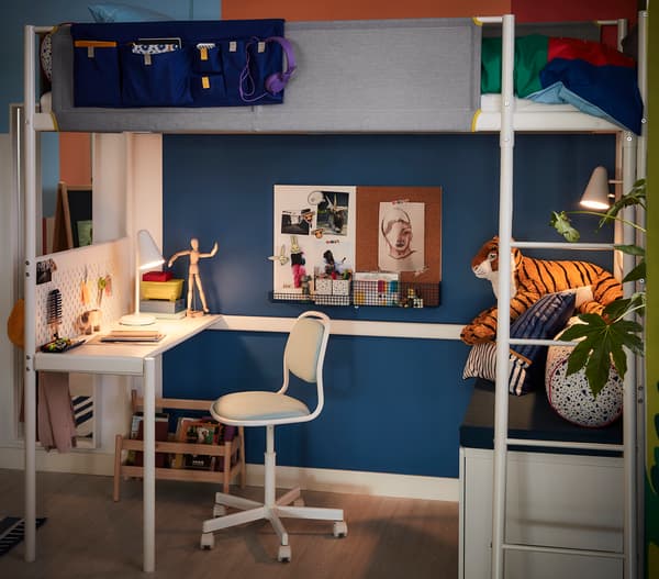 ブルーの壁に白いロフトベッドを合わせた子ども部屋。下段にデスクと収納を配置した機能的な空間。